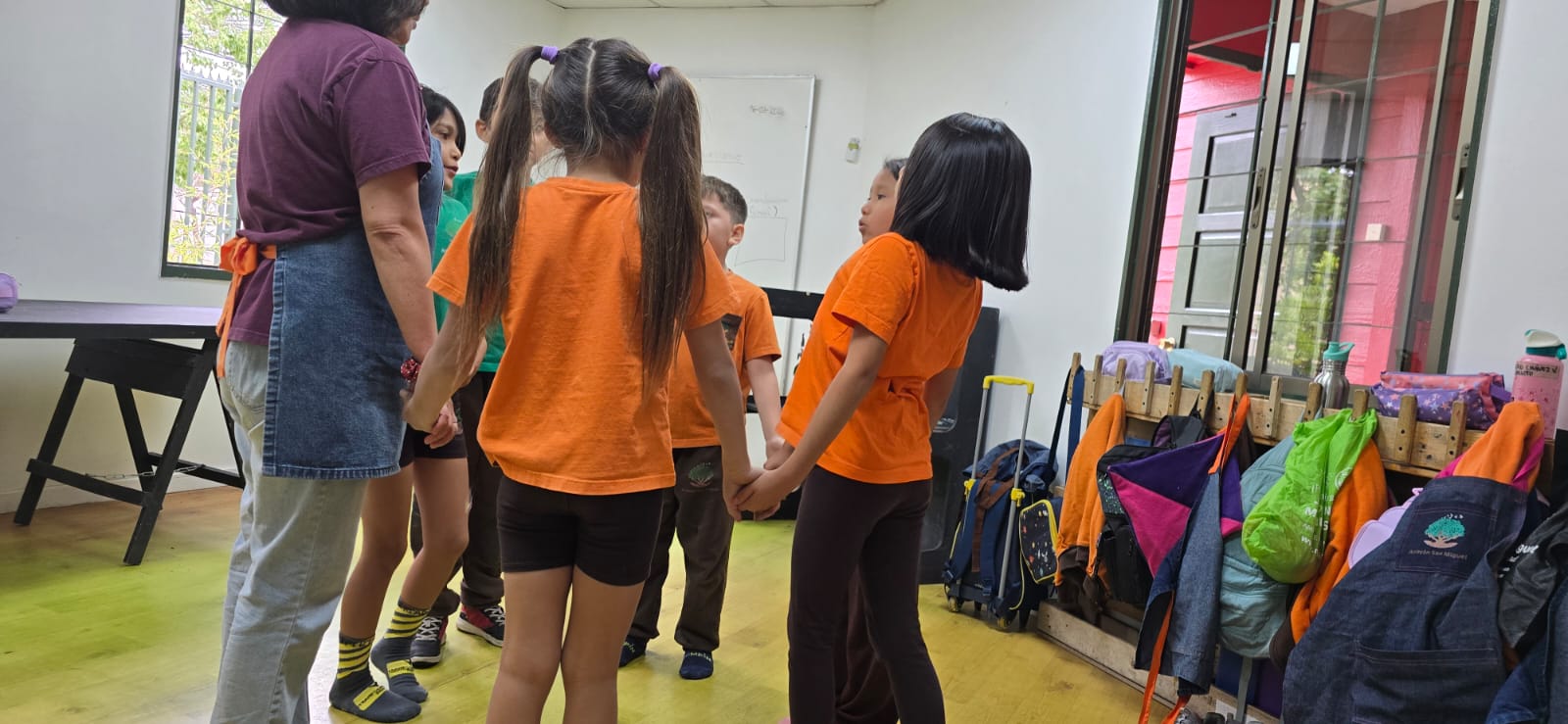 Niños y niñas tomados de la mano con su educadora